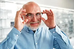 Senior man adjusting his glasses inside an optical shop