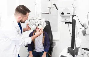 A man in a white lab coat is adjusting a machine on a boy's face in a white room.