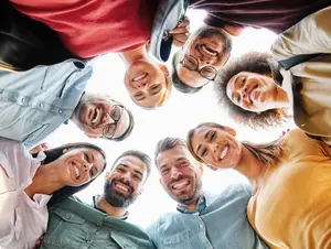 A group of diverse people smiling and looking at the camera in a circle formation