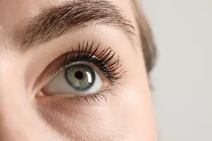 Close-up view of a woman's eye with eyelashes and eyebrows.