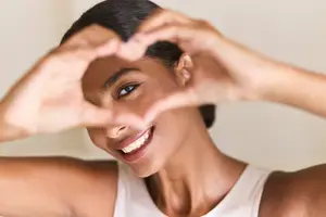 Woman smiling and posing with her hands in the shape of a heart
