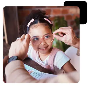 A girl is getting her glasses adjusted by an adult wearing a watch and bracelet.