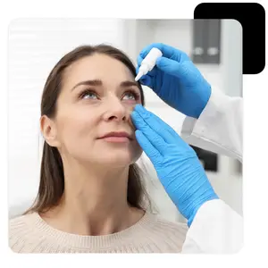 A woman in a white sweater is getting her eye checked by a doctor in a white coat and blue gloves.