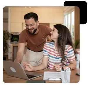 A couple looking at a laptop screen together. The man is standing behind the woman.