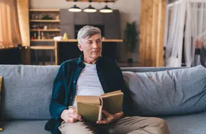 A man sitting on a couch reading a book