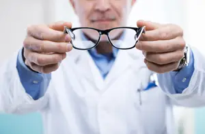 Doctor holding black eyeglasses with metal frame.