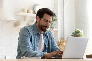 Man sitting at a table working on a laptop