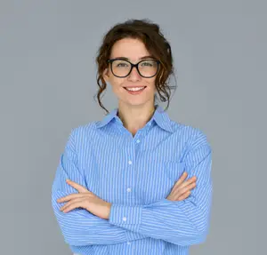 A woman in a blue striped shirt and glasses with her arms folded and smiling