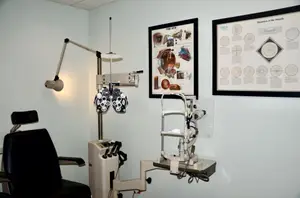 An eye examination room with two eye examination machines, a lamp, and a chair.