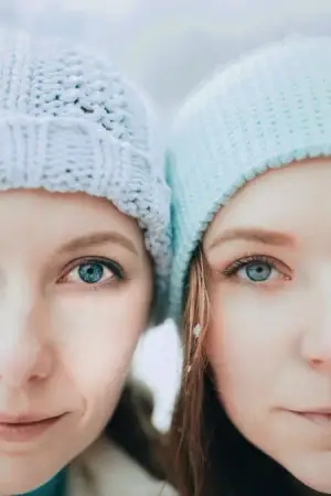 Two girls wearing knitted hats and smiling for the camera