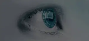 A close-up view of a human eye with a blue iris and a black pupil, set against a gray background