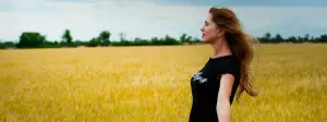 A woman standing in a wheat field with long hair blowing in the wind