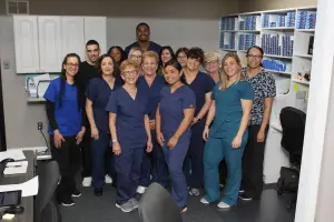 A group of medical professionals are posing for a photo in a room with white cabinets and shelves.