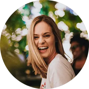 A smiling woman with blonde hair and a white shirt standing outdoors