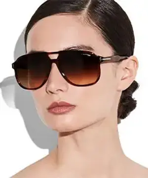 A woman with brown hair wearing sunglasses and makeup