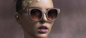 A woman wearing a gold headpiece and sunglasses with a serious expression