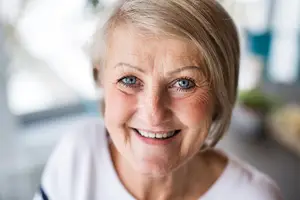 Close up of a woman with short hair and smiling with a white shirt