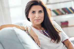 Portrait of a woman sitting on a couch, smiling and posing for a photo.