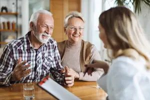 Senior couple smiling and talking to a woman at a table