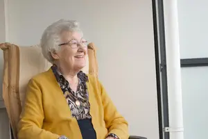 An elderly woman in a wheelchair smiling at the camera