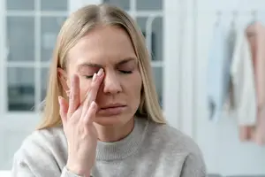 Woman with a headache holding her face in a room
