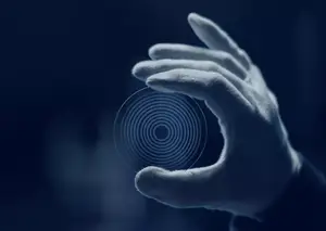 Hand holding circular object with spiral design on a dark background