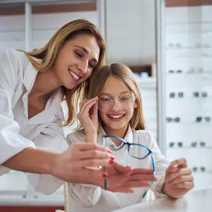 Woman and girl smiling and looking at glasses in an optometrist's office