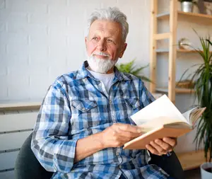 A man sitting on a chair reading a book
