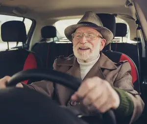 Elderly man driving a car with a smile on his face