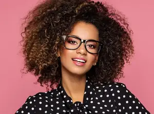 Woman wearing glasses and polka dot blouse smiling at the camera