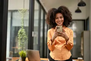 A woman takes a selfie in her office while smiling.