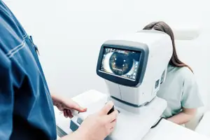 A doctor is examining a patient's eye with an ophthalmoscope in an eye clinic.