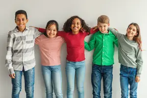 Five children standing together with arms around each other posing for a photo