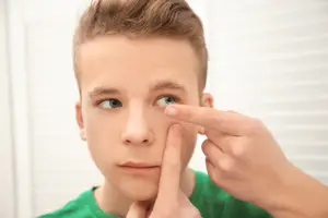 A person is trying to insert a contact lens into his eye