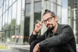 business man adjusting glasses outside building