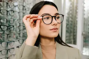A woman adjusting glasses in a room with many glasses on display