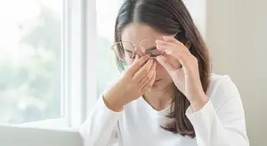 woman holding her glasses with her hand covering her eyes