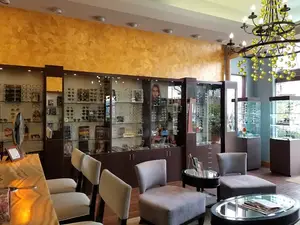 A shop with chairs, tables, and a glass display case with glasses and other items inside