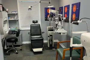 An examination room with an optometrist chair and eye diagnostic equipment