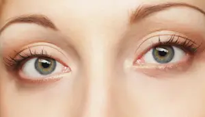 Close-up of a woman's eyes with long eyelashes and a slight redness on the right eye.