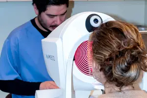 A man is operating a machine to check a woman's eyes in a medical setting