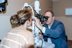 An eye doctor is examining a woman's eyes with a device