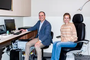 A man and a woman are smiling and posing for a picture in an office room