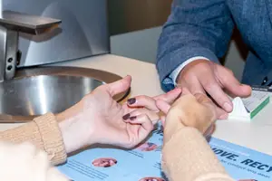 A woman is showing her contact lenses to a man who is wearing a suit in a clinic.