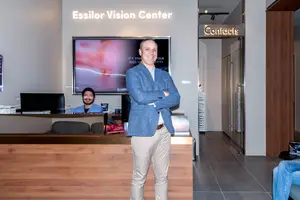 A man stands in front of a reception desk with another man sitting at a desk behind him