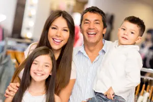 A family with a man, a woman, and two kids are smiling and posing for a photo in a clothing store