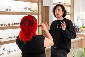 A man and a woman are standing in front of a display of glasses in a store