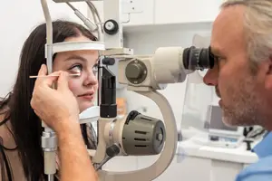 A doctor is examining a patient's eye with a microscope
