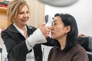 A woman is having her eyes examined by another woman in a medical setting