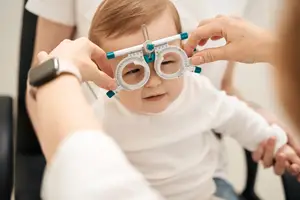 A baby is having their eyes checked by a doctor using a special tool.